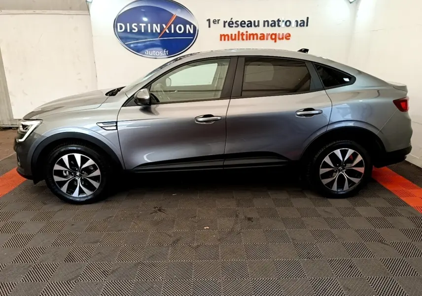 Profil droit d'une Renault Arkana gris clair 2023, avec jantes alliage et lignes fluides de SUV coupé.