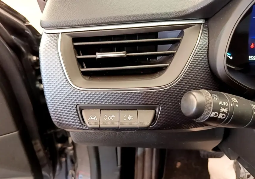Détail du tableau de bord gris clair côté gauche avec aérateur et commandes d'assistance sur Renault Arkana Evolution E-Tech 2023.