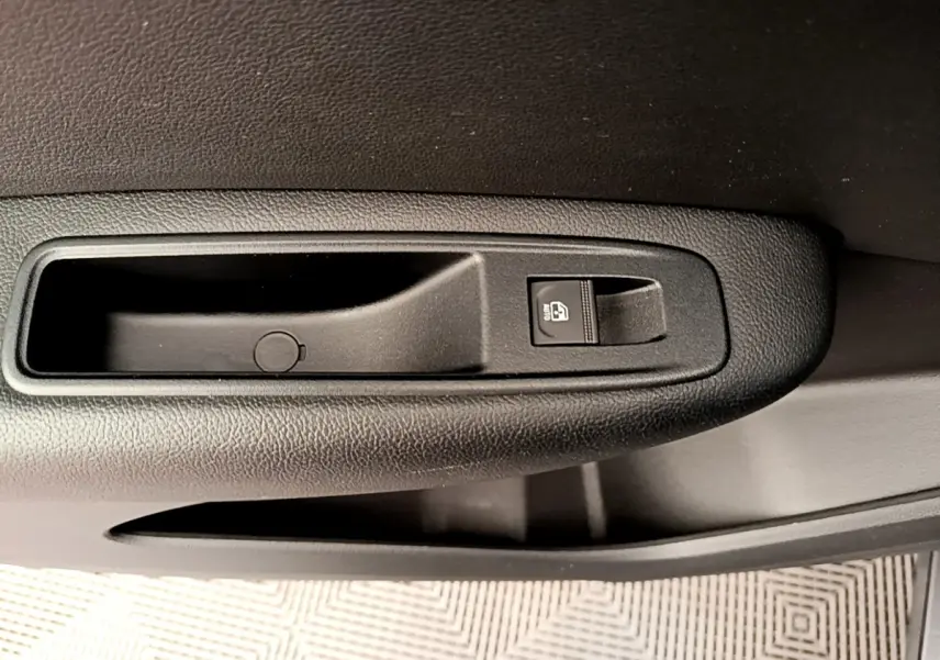 Gros plan sur la commande de lève-vitre noir dans la portière intérieure d'une Renault Arkana gris clair.