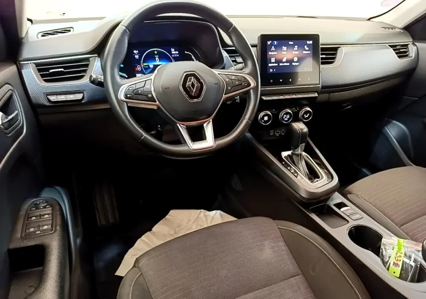 Vue intérieure de face du tableau de bord et volant noir du Renault Arkana Evolution E-Tech 2023 avec écran tactile central.