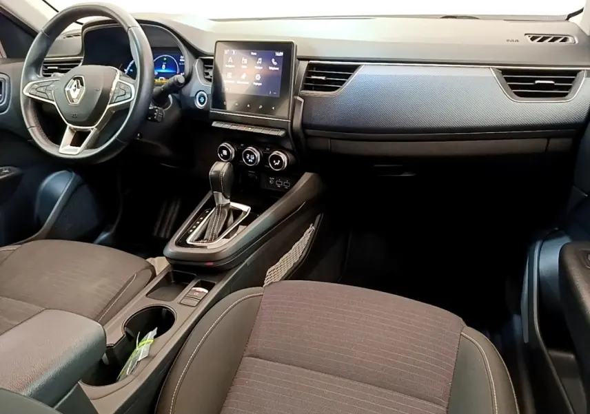 Vue intérieure avant du Renault Arkana gris clair 2023, tableau de bord avec écran tactile central et volant multifonctions.