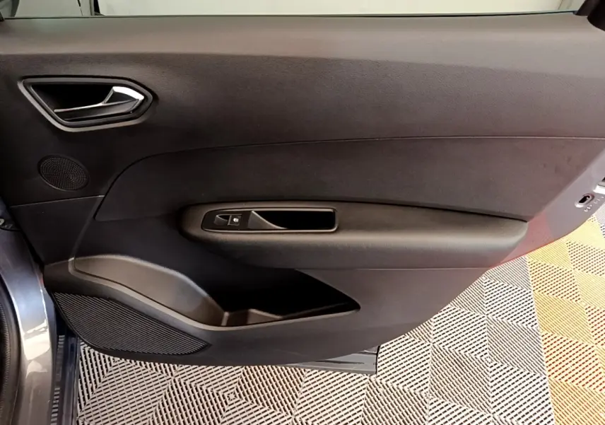 Vue intérieure de la porte côté gauche d'un Renault Arkana gris clair, avec poignée et commande de fenêtre noire.