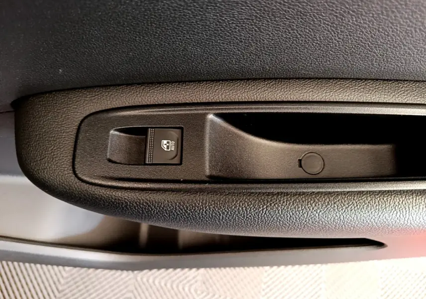 Gros plan sur la commande de lève-vitre côté conducteur dans l’habitacle noir du Renault Arkana gris clair.