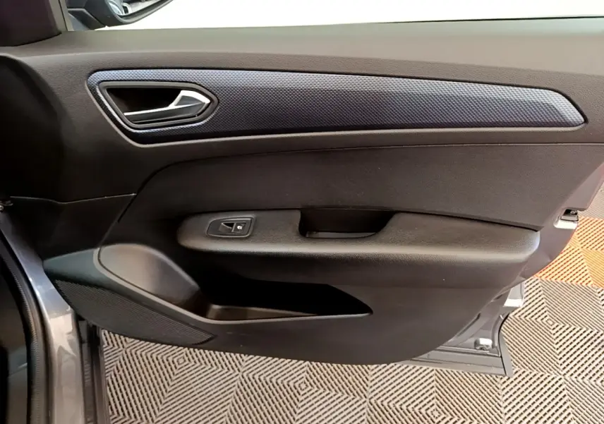 Vue rapprochée de la porte avant gauche gris clair du Renault Arkana Evolution E-Tech avec poignée et commande de vitre.
