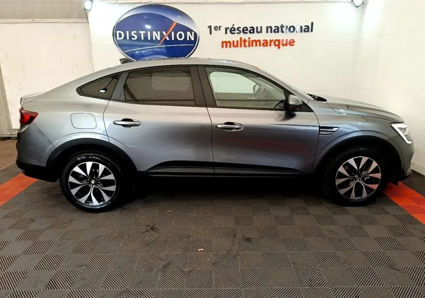 Profil droit d’un Renault Arkana gris clair 2023 Evolution E-Tech full hybrid, avec jantes alliage et lignes fluides.