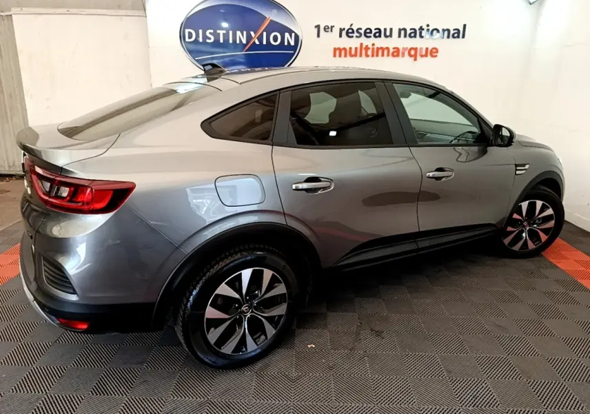 Renault Arkana gris clair en vue 3/4 arrière droit, soulignant ses lignes fluides et ses jantes bicolores modernes.