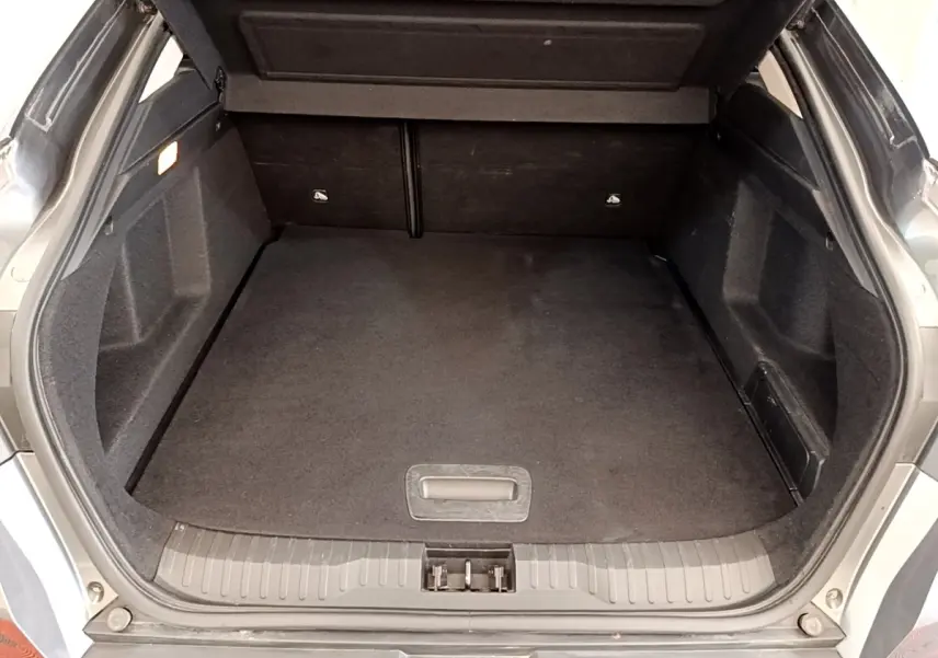 Coffre ouvert vu de l'arrière d'une Renault Arkana gris clair, espace de chargement propre et spacieux.