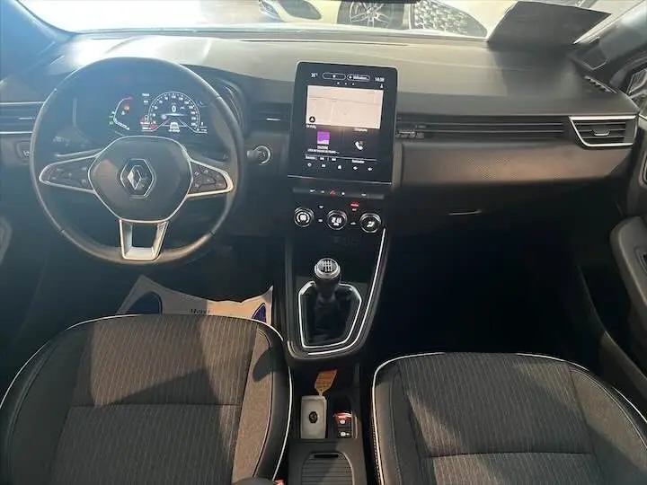 Vue intérieure avant de la Renault Clio V 1.0 TCE 90 Intens avec tableau de bord moderne et levier de vitesse manuel.
