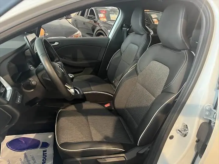Intérieur de la Renault Clio V blanc nacré, vue côté gauche sur les sièges avant en cuir noir avec surpiqûres blanches.