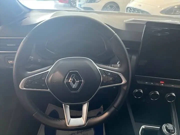 Vue rapprochée du volant noir de la Renault Clio V avec commandes intégrées et tableau de bord moderne.