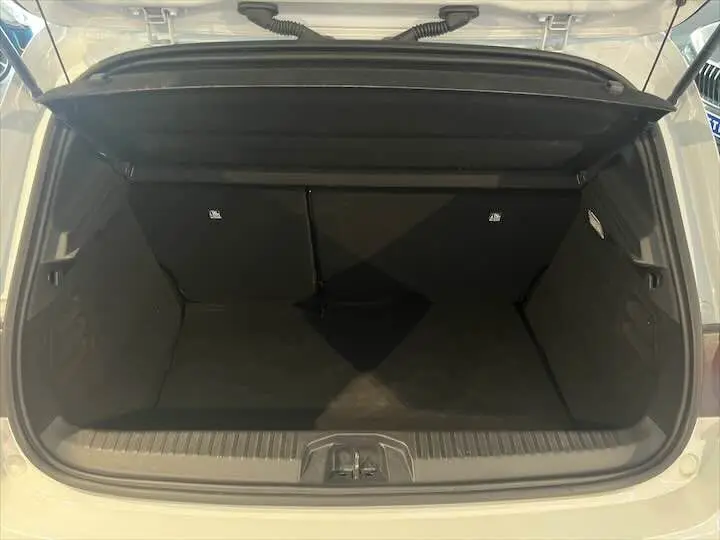 Coffre ouvert vu de l'arrière d'une Renault Clio V blanc nacré métal, montrant l'espace de chargement vide.