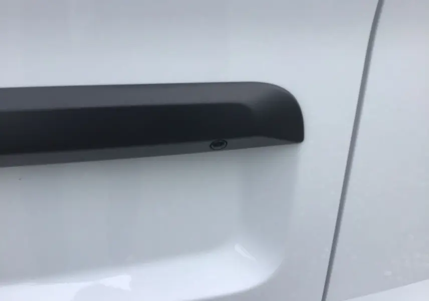 Poignée de porte noire en gros plan sur la portière blanche côté droit du Citroën Jumpy Cabine Approfondie.