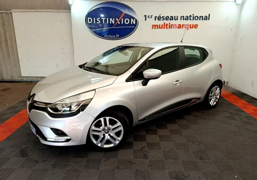 Renault Clio Business TCe 90 gris clair vue 3/4 avant droit dans un showroom avec sol noir et orange.
