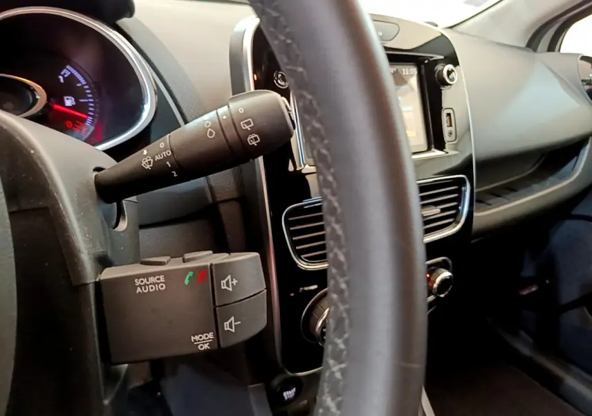 Gros plan sur le volant cuir et le tableau de bord tactile de la Renault Clio Business gris clair, vue côté conducteur.