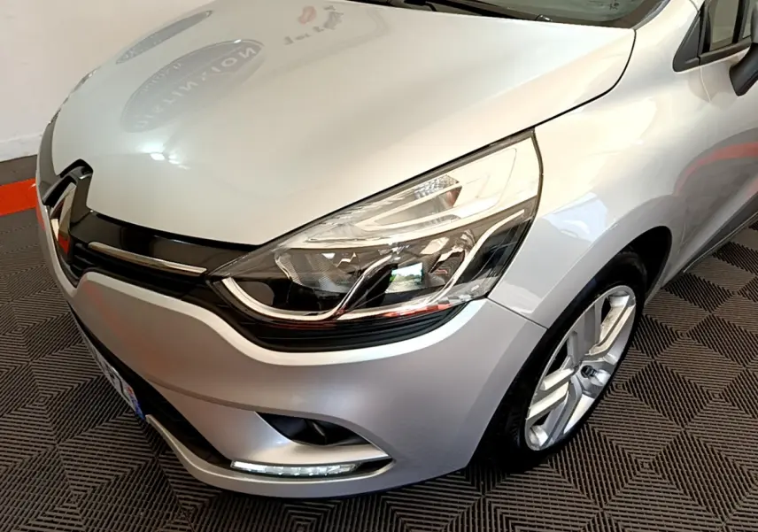 Vue 3/4 avant droit d'une Renault Clio Business TCe 90 gris clair avec phares LED et jantes alliage visibles.