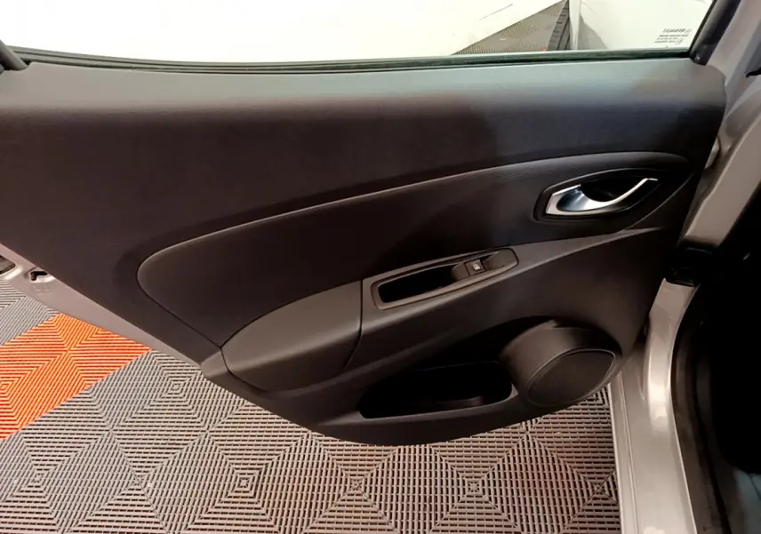 Vue rapprochée de la porte arrière droite gris clair d'une Renault Clio 2019 avec poignée et commande de vitre noire.