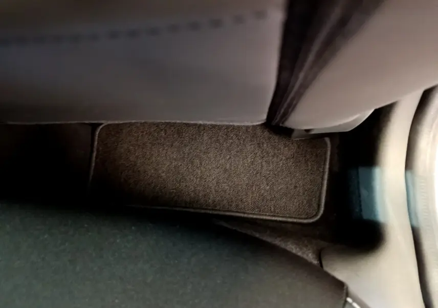 Gros plan sur le tapis de sol côté passager avant d'une Renault Clio Business TCe 90 gris clair, intérieur sombre.