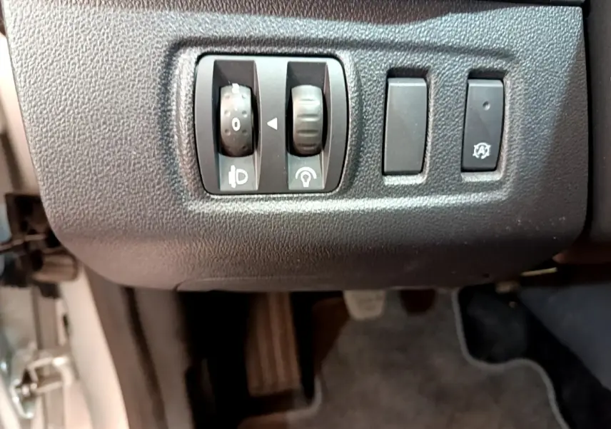 Gros plan sur les commandes de réglage des phares et arrêt automatique dans l'habitacle d'une Renault Clio Business gris clair 2019.