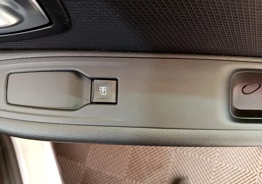 Gros plan sur la commande de lève-vitre côté conducteur d'une Renault Clio Business gris clair, intérieur noir.