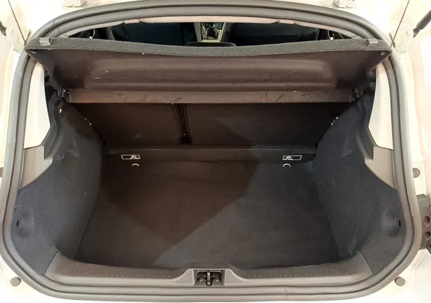 Coffre ouvert d'une Renault Clio gris clair, vue de dessus montrant l'espace de chargement vide et la tablette arrière.