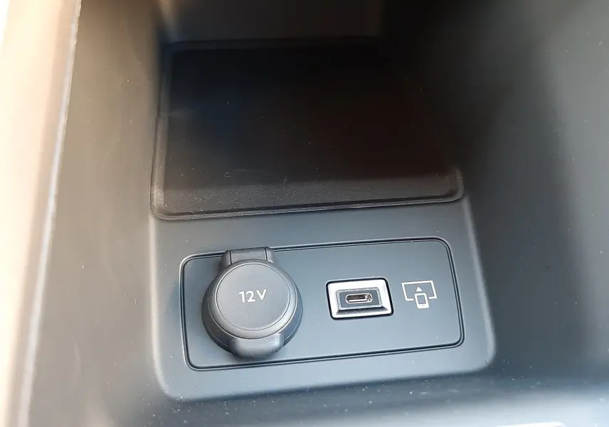 Prise 12V et port USB-C en gros plan dans la console centrale noire de la Peugeot 308 Bleu Obsession 2025.