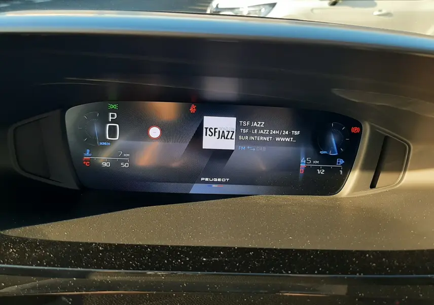 Tableau de bord numérique de la Peugeot 308 Bleu Obsession, affichant la radio TSF Jazz et les informations de conduite.