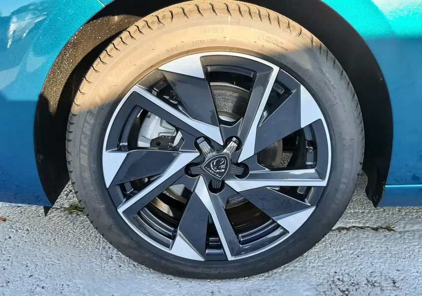 Gros plan sur la roue avant droite d'une Peugeot 308 Bleu Obsession avec jante alliage bicolore moderne.