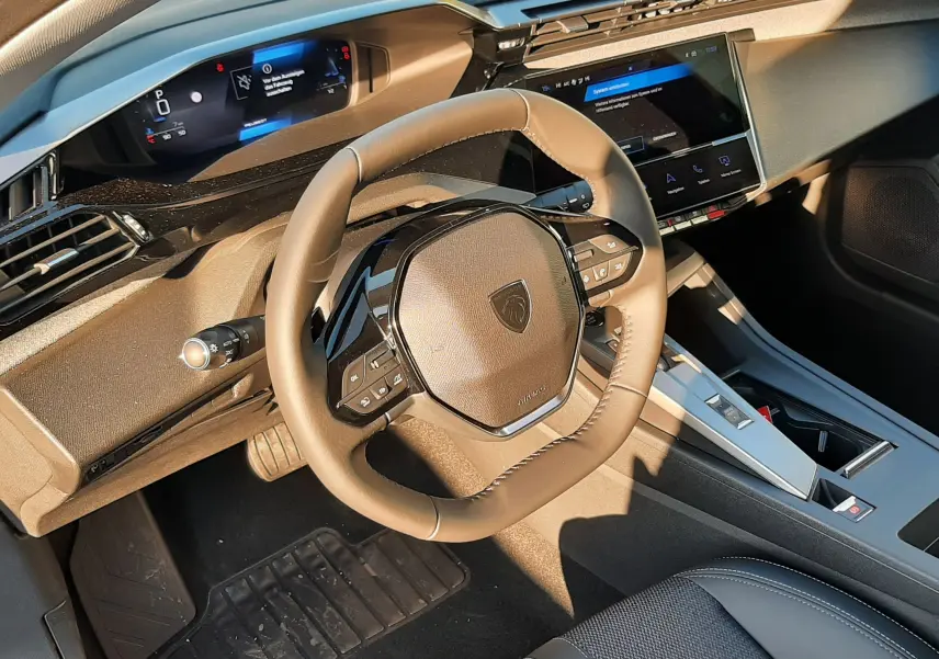 Vue intérieure du poste de conduite de la Peugeot 308 2025, volant compact et tableau de bord numérique moderne.
