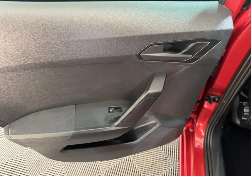 Vue rapprochée de la portière avant gauche noire de la SEAT IBIZA rouge 2024, avec poignée et commande de vitre électrique.