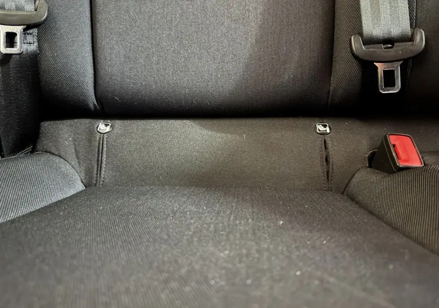 Gros plan sur la banquette arrière noire de la SEAT Ibiza 2024 avec attaches Isofix et boucle de ceinture rouge.