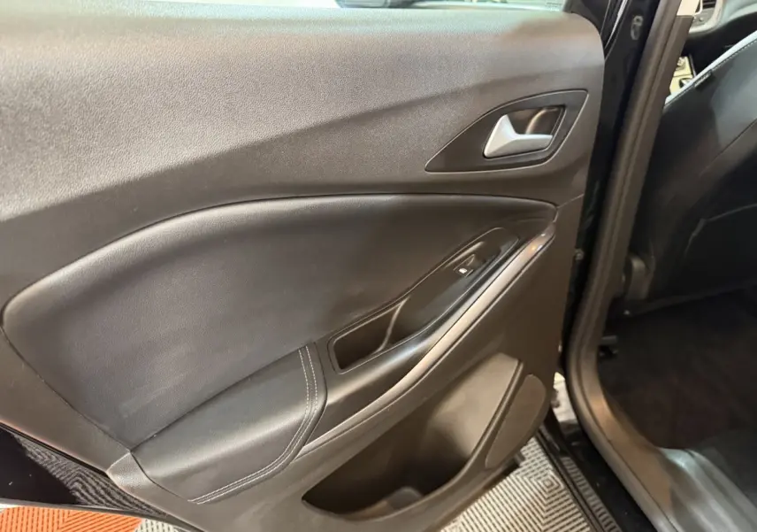 Vue intérieure sur la porte arrière gauche noire de l’Opel Grandland X avec poignée et commande de vitre électrique.