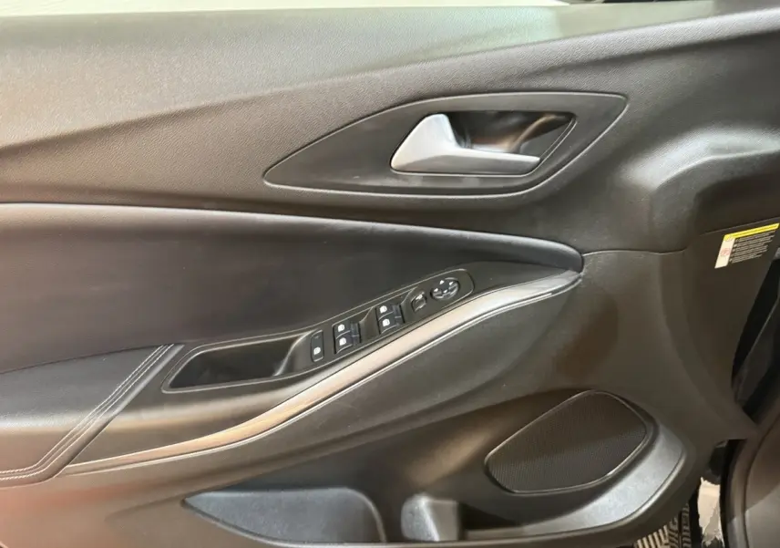 Vue intérieure du panneau de porte côté conducteur noir de l'Opel Grandland X 2021 avec commandes électriques et poignée argentée.