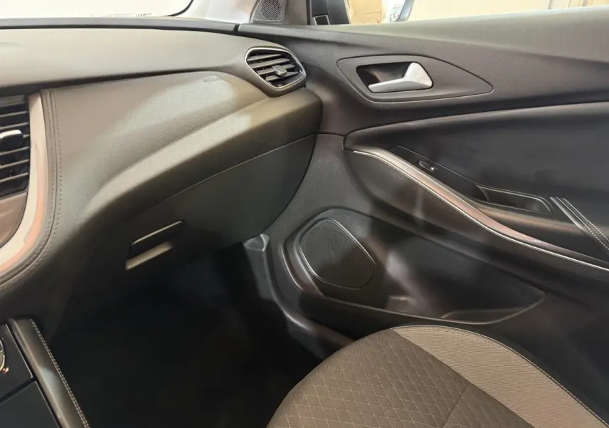 Vue intérieure côté passager de l’Opel Grandland X 2021, avec tableau de bord et porte en noir et gris.