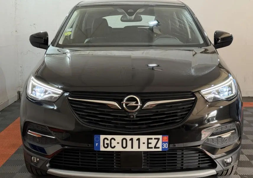 Vue frontale d'un Opel Grandland X noir avec phares LED allumés et calandre noire distinctive.