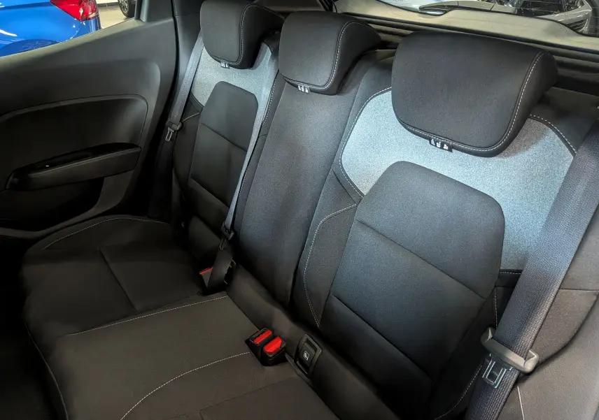 Vue intérieure des sièges arrière en tissu noir et gris de la Renault Clio V, avec ceintures de sécurité visibles.