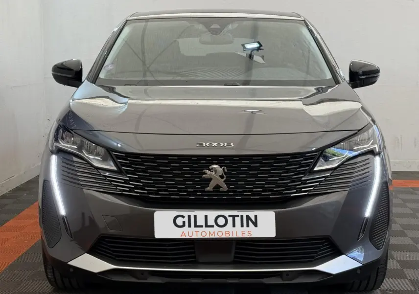 Vue frontale d’un Peugeot 3008 gris foncé avec calandre noire et feux LED verticaux allumés.