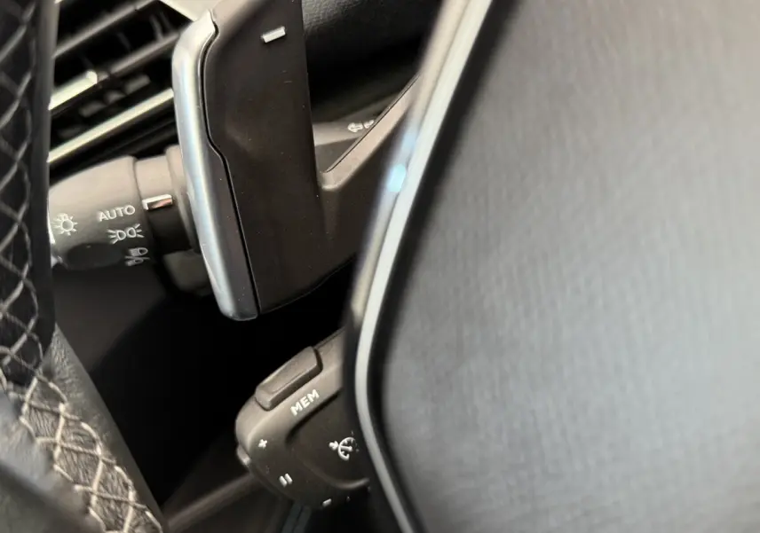 Détail du volant cuir noir et des commandes multifonctions du Peugeot 3008 PureTech 130 gris foncé, vue rapprochée.