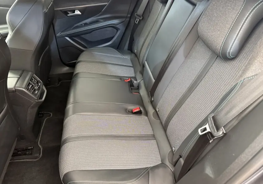 Vue intérieure des sièges arrière du Peugeot 3008 gris foncé, montrant la banquette mixte tissu et cuir avec ceintures et appuie-têtes.