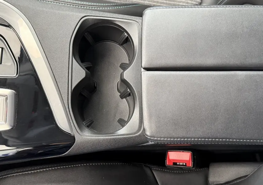 Gros plan sur la console centrale noire avec porte-gobelets et accoudoir cuir du Peugeot 3008 gris foncé 2022.