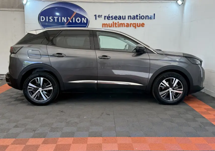 Vue de profil côté gauche du Peugeot 3008 gris foncé 2022 dans un showroom avec sol à damiers gris et orange.