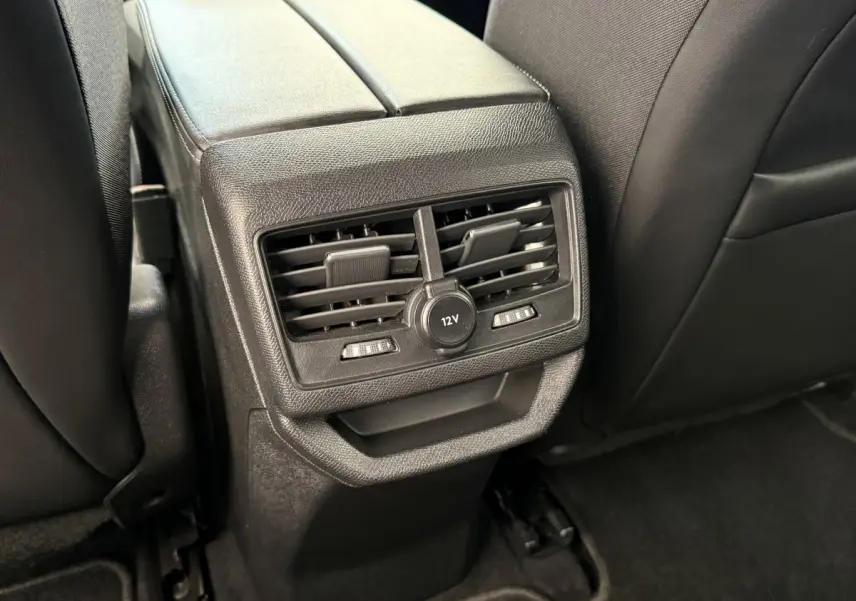 Détail des aérateurs arrière et prise 12V noirs sur la console centrale entre les sièges arrière d’un Peugeot 3008 gris foncé.