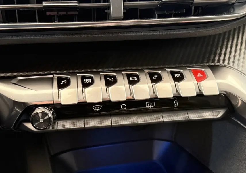 Gros plan sur la rangée de boutons chromés du tableau de bord du Peugeot 3008 gris foncé, 2022, version Allure.