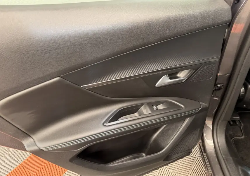 Vue rapprochée de la porte avant droite du Peugeot 3008 gris foncé, avec garniture noire et commandes de vitre.
