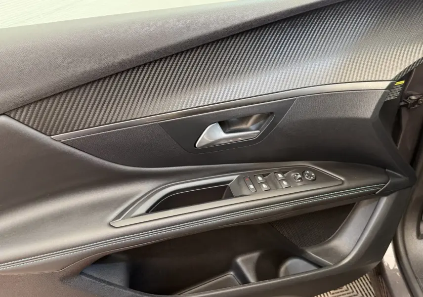 Gros plan sur la porte avant gauche du Peugeot 3008 gris foncé, avec commandes des vitres et insert effet carbone.