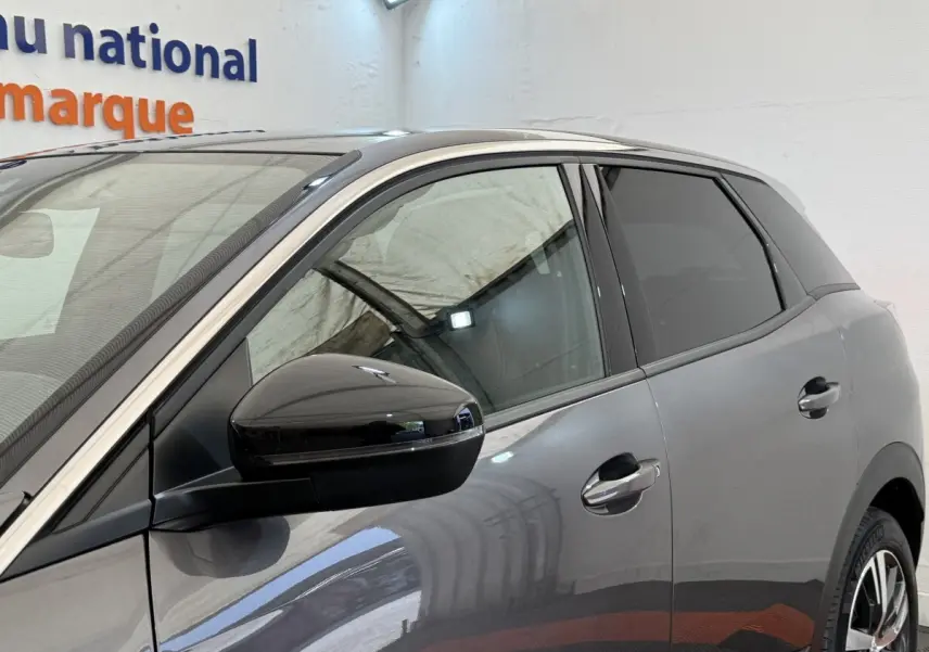 Vue côté gauche avant d’un Peugeot 3008 gris foncé avec rétroviseur noir brillant et poignées ton caisse.