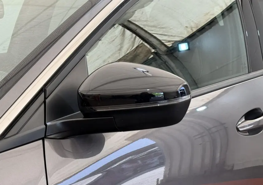 Gros plan sur le rétroviseur droit noir brillant d’un Peugeot 3008 gris foncé, avec la portière visible en arrière-plan.