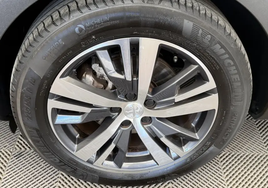 Gros plan sur la jante alliage 18 pouces et pneu Michelin d’un Peugeot 3008 gris foncé, version PureTech 130 Allure.