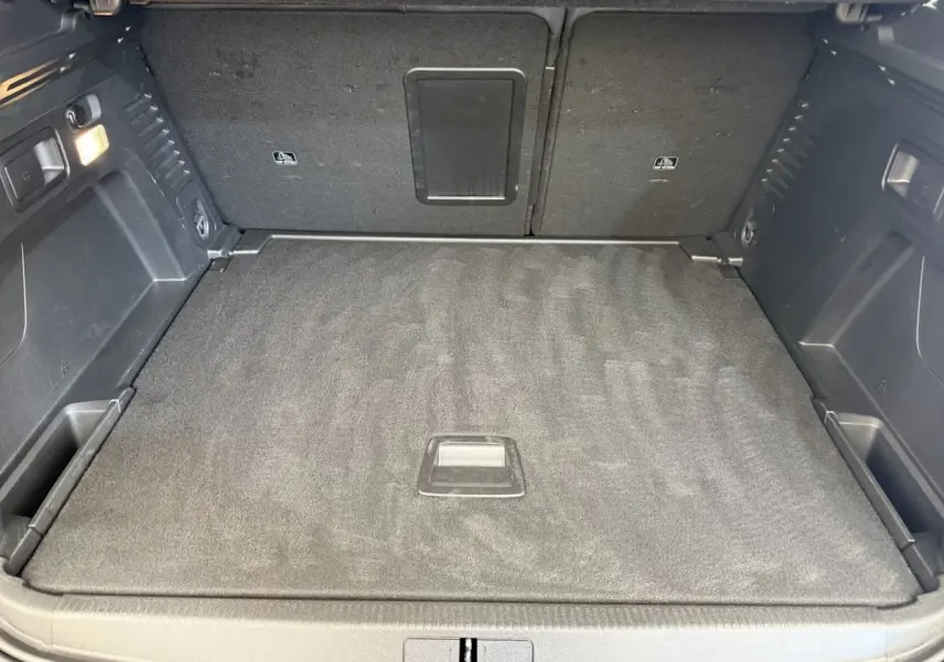 Vue intérieure du coffre spacieux et propre du Peugeot 3008 gris foncé, avec plancher plat et éclairage latéral.