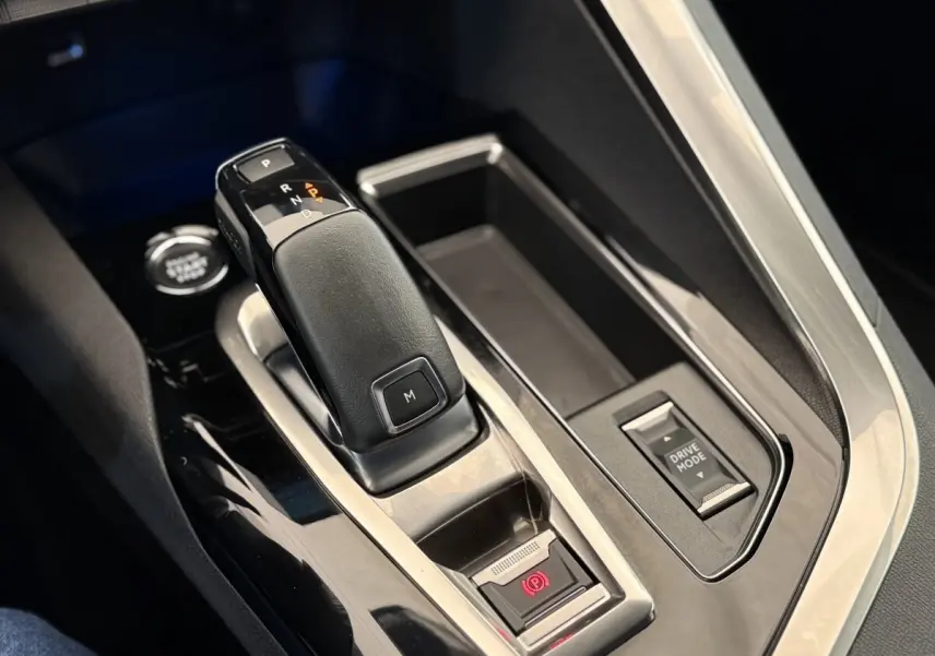 Gros plan sur la console centrale du Peugeot 3008 gris foncé, mettant en valeur le levier de vitesses automatique et le bouton Drive Mode.