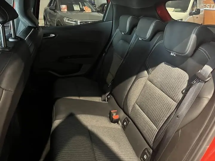 Vue intérieure des sièges arrière en tissu noir de la Renault Clio V rouge flamme métal, avec appuie-têtes et ceintures visibles.